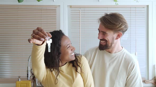 Smiling Multiethnic Heterosexual Couple Show the Keys to Their New House alt