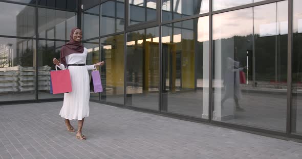 Woman Carrying Bags While Walking Near Shopping Mall alt