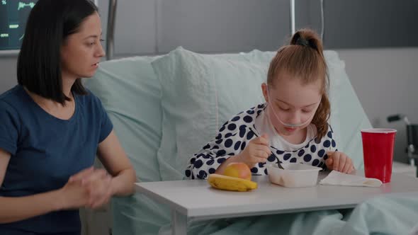 Mother Sitting Beside Sick Daughter While Eating Meal Lunch Recovering After Medical Surgery alt