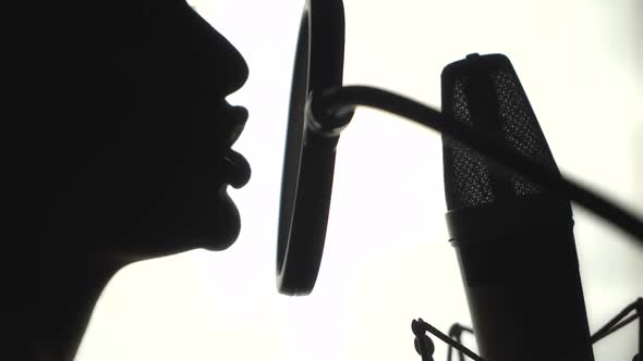 Silhouette of a woman singing a song in a recording studio. Black and White. alt