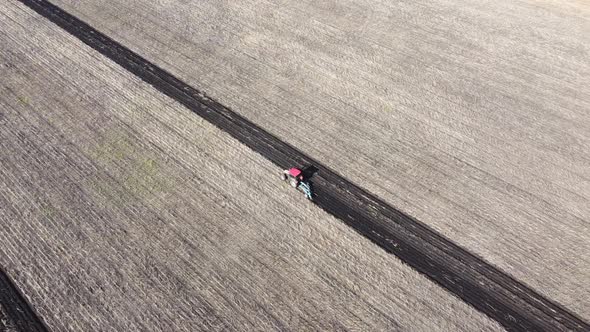 Shooting From Drone Flying Over Tractor with Harrow System Plowing Ground on Cultivated Farm Field