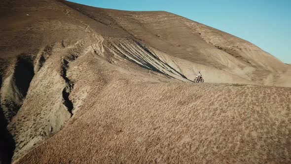 Drone View of Man on Motorbike Extremely Rides Across the Hills with Black Sea on Background 