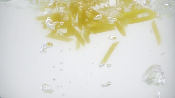 Cheap Tasteless Pasta Thrown Into the Muddy Boiling Water, Slow Motion on White Background, alt