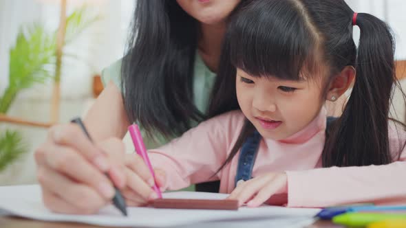 Asian loving parent with daugther having fun drawing and coloring picture enjoy activity at house. alt