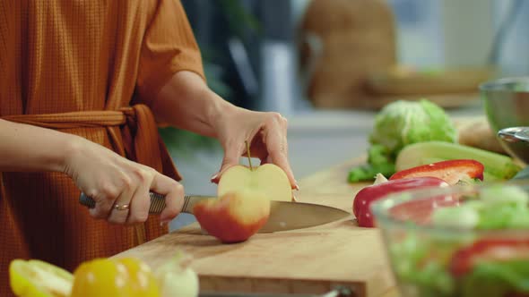 Woman Hands Cutting Red Apple in Kitchen. Housewife Cooking Vegetable Salad. alt