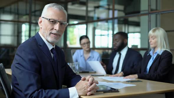 Elderly Company Director Looking Camera, Office Colleagues Discussing Strategy alt