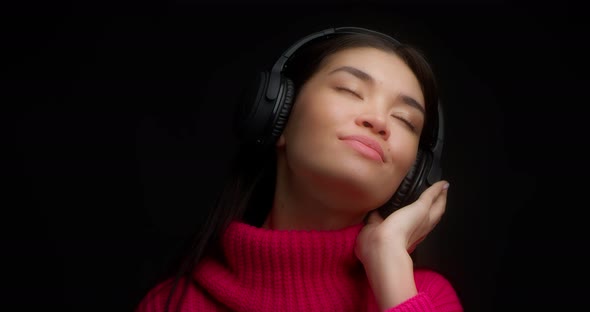 Cute Woman Enjoy Music with Wireless Headphones and Drinks From a Red Mug