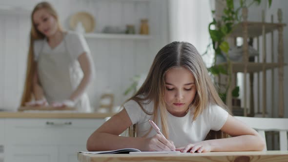 Teen Girl Daughter Child Schoolgirl Pupil Sits at Table Writes in Notebook Homework Study From Home alt