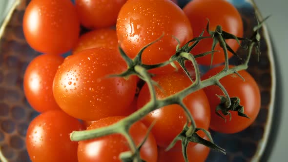 Juicy ripe cherry tomatoes spin on a blue plate top view alt
