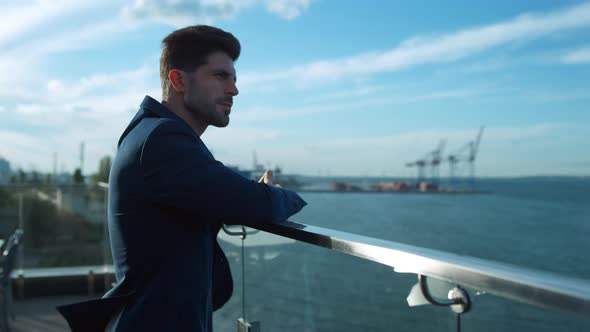 Thoughtful Businessman Looking Sea on Glass Terrace alt