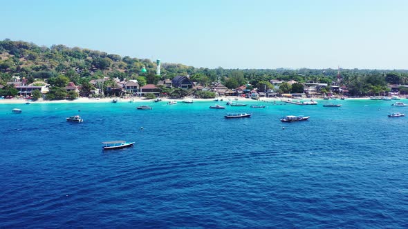 Boats on the surface of the vibrant blue waters and white sand of the Turks and Caicos Islands alt