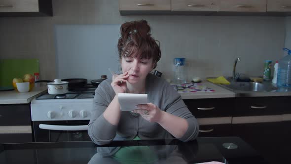 Woman Sits in the Kitchen at Home and Makes Plans Writes in a Notebook