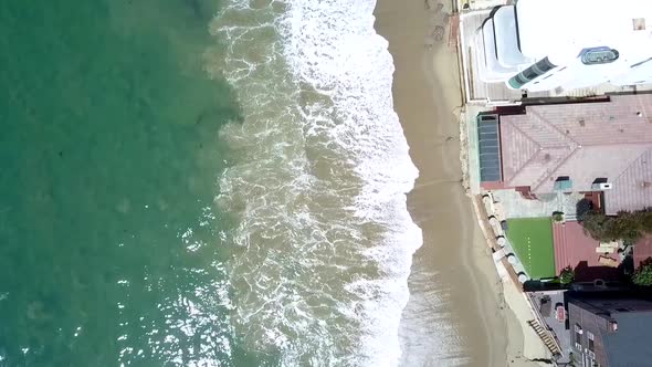 Slow motion coastline with big waves and beautiful family housesDaring aerial view flight bird's ey alt