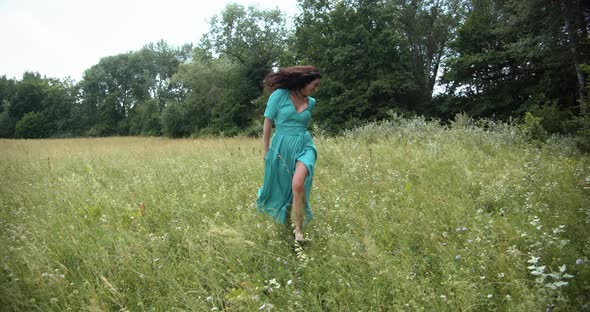 A Girl In A Long Dress Runs Across A Green Meadow alt