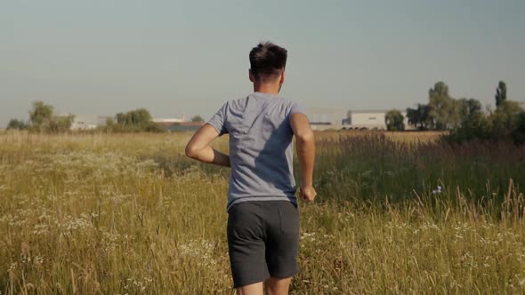 Running Man On Green Grass Field.Slow Motion Running Man Exercising On Trail.Man Running On Park alt