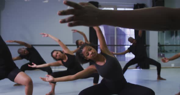 Multi-ethnic group of fit male and female modern dancers practicing a dance routine alt