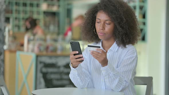 Successful Online Payment on Smartphone By African Businesswoman in Cafe alt