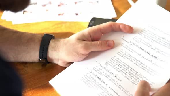 Man pausing to check smartwatch while reading document