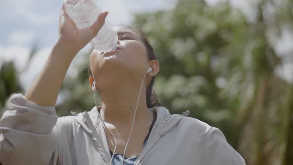 Portrait young Asian woman runner drink water after running.