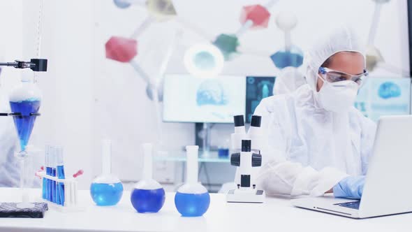 Female Scientist Working in a Modern Laboratory with Reagent in Test Tubes with Blue Liquid and alt