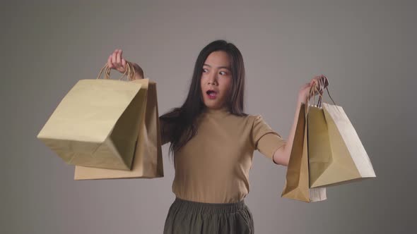 Confident asian woman happy holding shopping bag dancing smilling and looking at camera