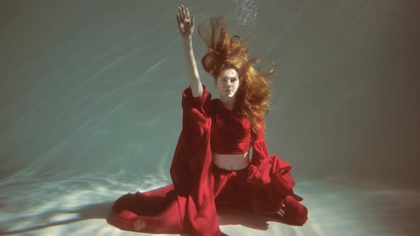 Attractive Redhaired Young Woman Swims Beautifully Underwater in a Red Dress alt