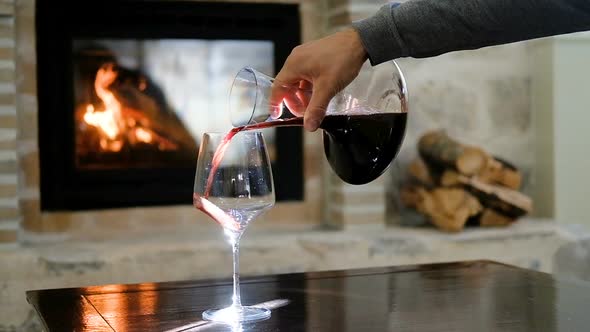 Glass and carafe with red wine on the background of the fireplace alt