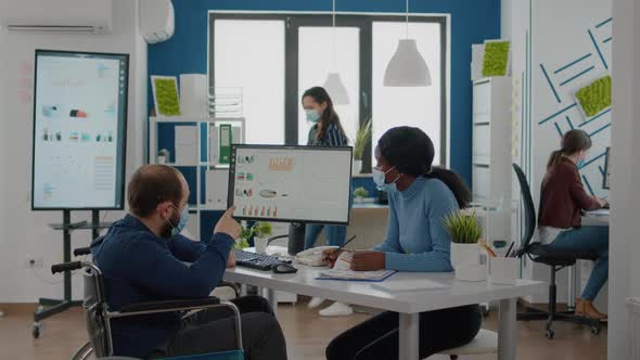 Paralysed Freelancer with Face Mask Discussing with Black Woman Partner alt