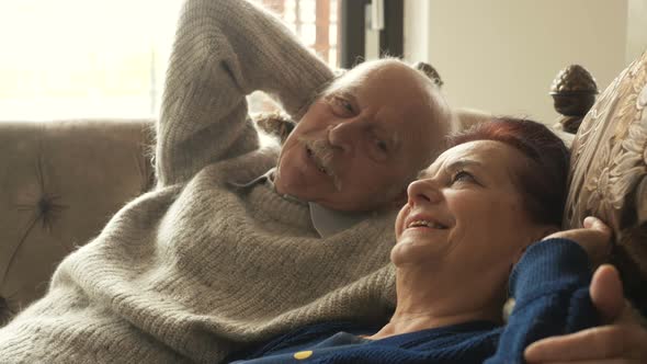Calm senior aged couple relaxing leaning on comfortable soft couch having healthy nap together, happ