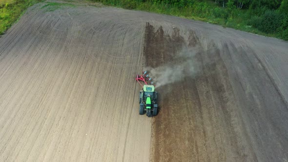 The tractor plows the soil in the field. alt