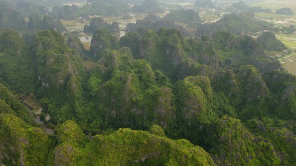 Aerial Shot of Beautiful Limestone Mountains with Passes Carved By a River in Ninh Binh Region a alt