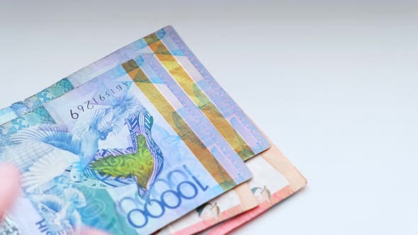 Man recalculates banknotes of Republic of Kazakhstan tenge, five, ten twenty thousand denominations. alt