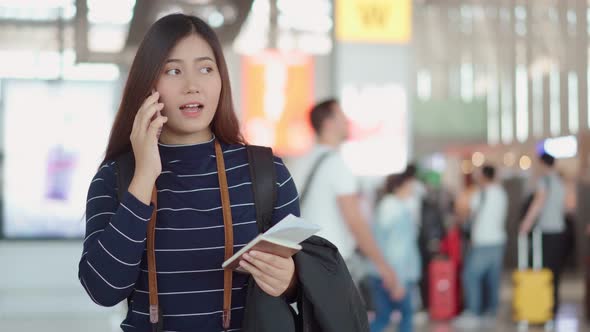 Young female traveler talking with smartphone to someone at airport alt