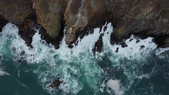 Aerial view of ocean waves splashing in the rocky beach alt