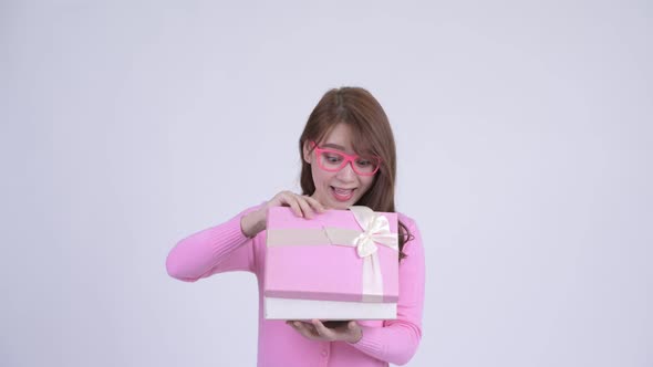 Young Happy Asian Nerd Woman Opening Gift Box and Looking Surprised alt