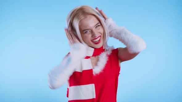 Sexy Young Woman in Santa Claus Costume Dancing with Headphones