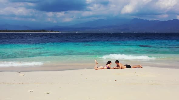 Two people sunbathe on perfect bay beach wildlife by shallow sea and white sand background of Bali a alt