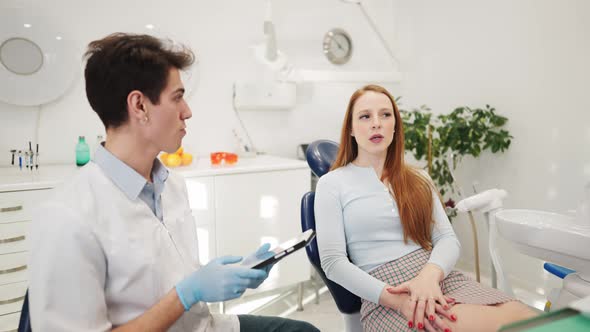 Male Dentist Discussing Treatment Options with Female Patient After Dental Examination alt