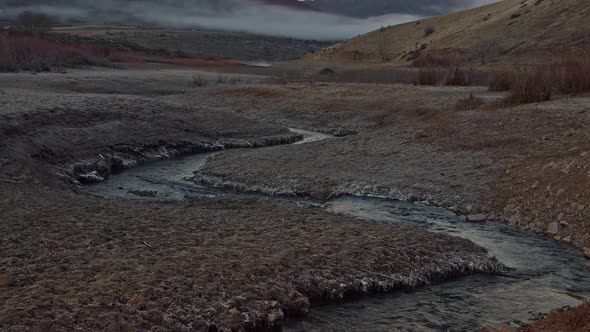 Winding river flowing towards mountain tilting up to the peak alt