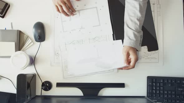 The Engineer Opens a Folder with Drawings and Works at the Table alt