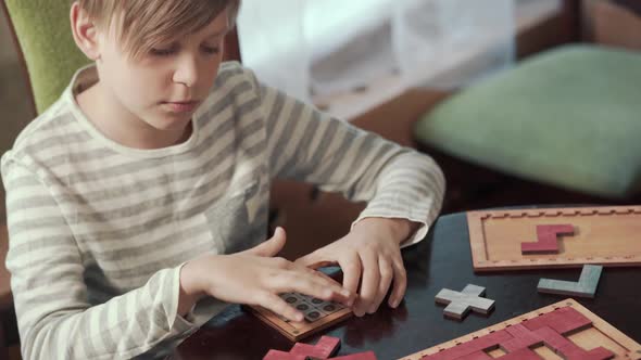 The Boy Collects a Puzzle While Sitting at a Table alt