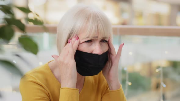 Closeup Unhappy Caucasian Middleaged Woman in Medical Mask Sitting Indoors Holding Hands Behind Head alt