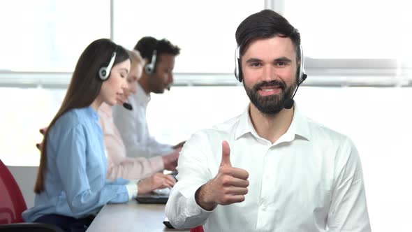 Young Handsome Man with Beard Showing Thumb Up in Office. alt