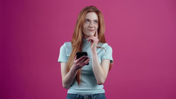 The Charismatic and Redhaired Teenager Looks at the Phone and Thinks About What to Answer to the alt