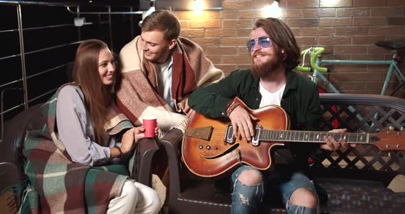 Friends Playing Guitar and Relaxing in Evening