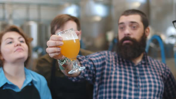 Specialist Standing with Glasses of Beer Explaining Brewing Process To Visitors alt