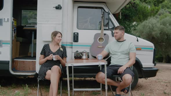 Young adult Couple by Camper van drinking coffee while camping on road trip in Montenegro alt