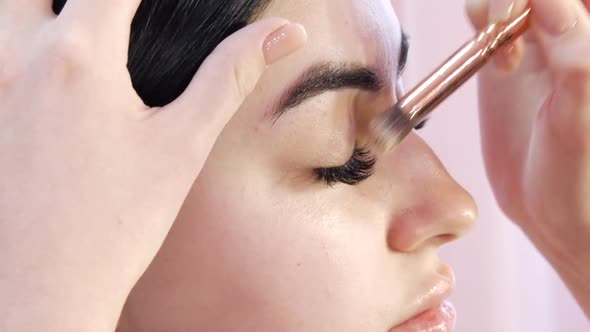 Girl Stylist Makes a Stylish Bright Makeup to a Young Beautiful Woman Model in the Studio alt