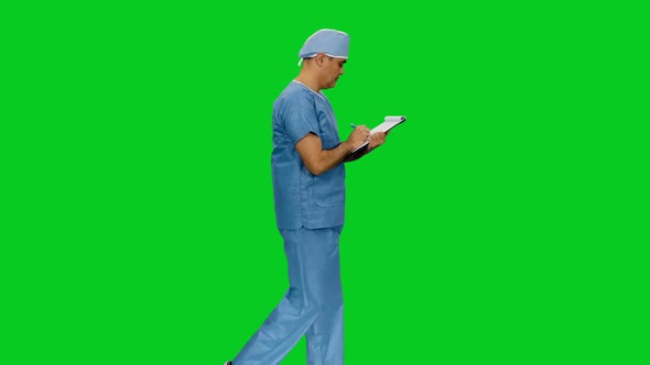 Asian Doctor In Uniform Writing On Clipboard While Walking 