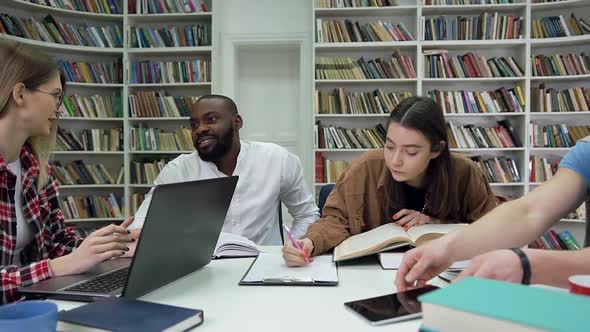 Smiling Multiracial Youth which Working Together Over their University Task in Reading Room alt